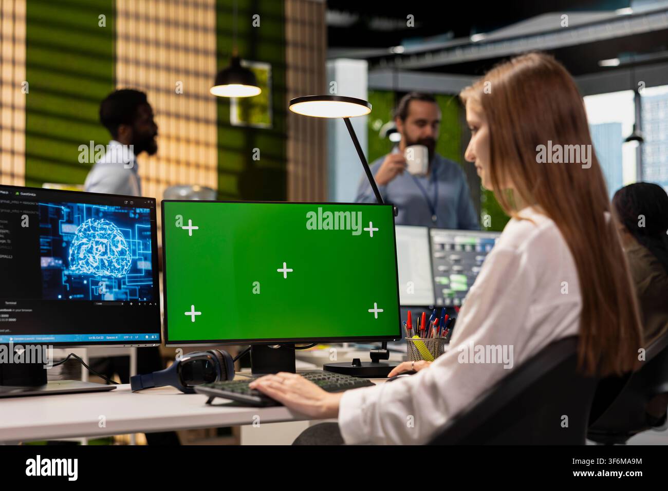 Junior dev in tech startup uses AI on green screen PC to optimize performance and forecast issues. Young female engineer writing code in office, training machine learning models using mockup computer Stock Photo