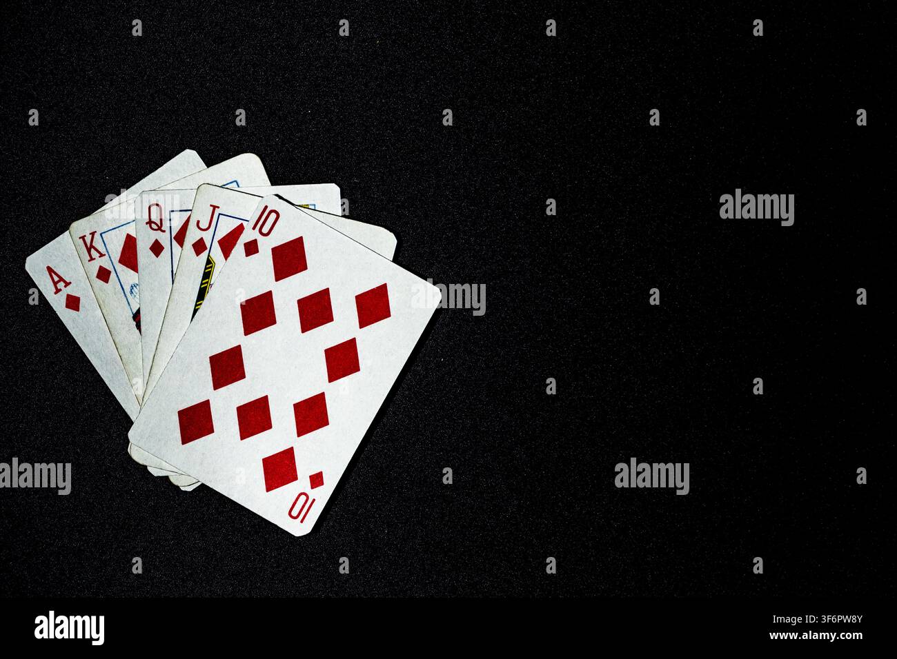 Five playing cards. A royal flush ten, jack, queen, king ace of diamonds, on a dark sparkly fabric back ground, suggesting success and being the best. Stock Photo