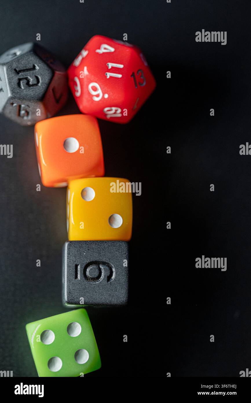 Strategic board game concept featuring polyhedral and standard dice on a dark surface Stock Photo