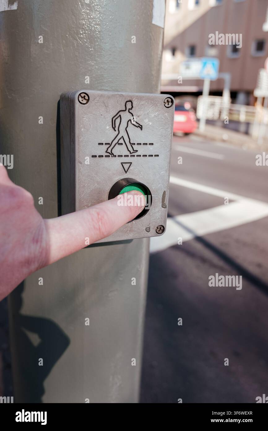Hand pressing green pedestrian crossing button on a city street Stock Photo