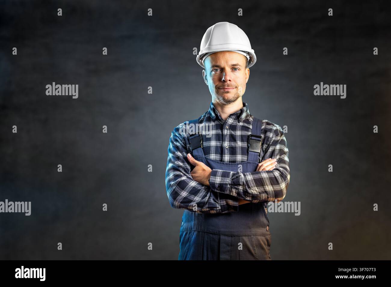 Confident Construction Engineer in White Hardhat and Overalls Looking at Camera Stock Photo