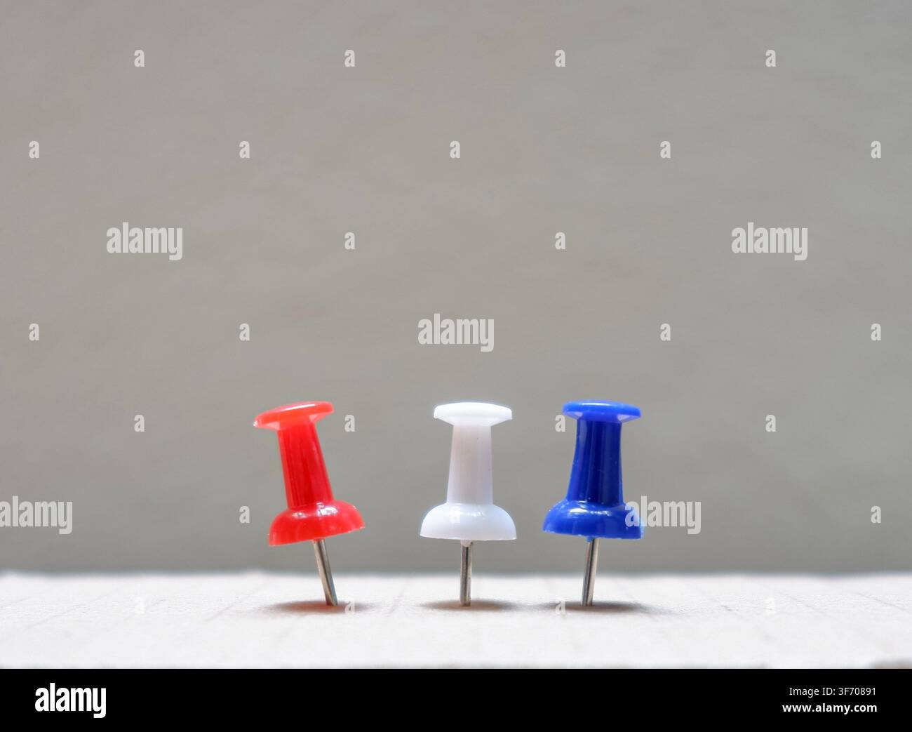 Red, white and blue push pins pinned on white surface Stock Photo