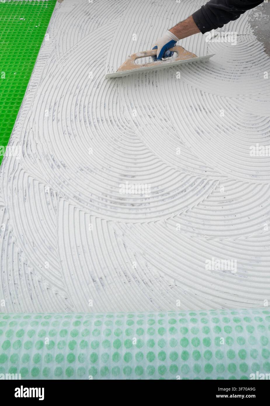 Worker Spreading White Tile Adhesive With Notched Trowel Stock Photo