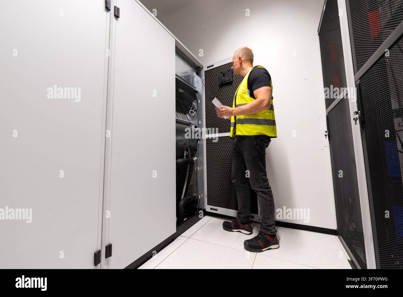 HVAC technician inspecting cooling infrastructure in a data center server room Stock Photo