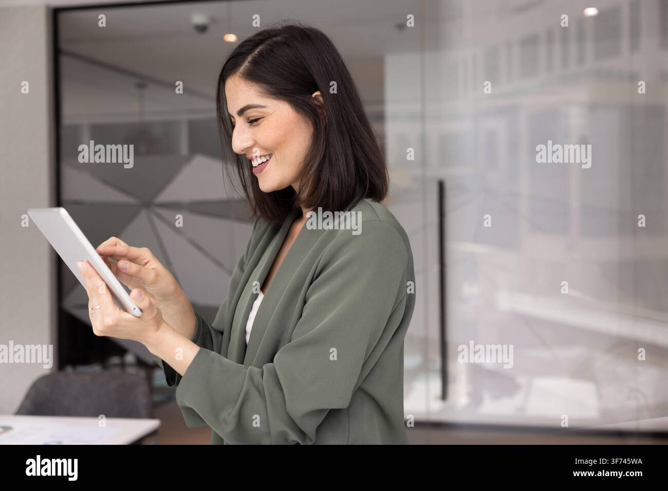 Confident professional businesswoman checking emails on smartphone in modern office Stock Photo