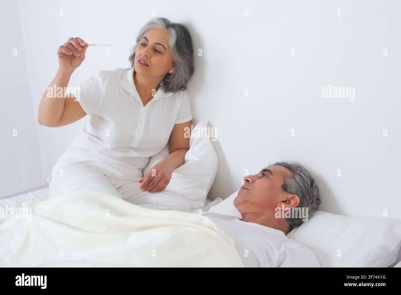 Wife checking husband's fever Stock Photo