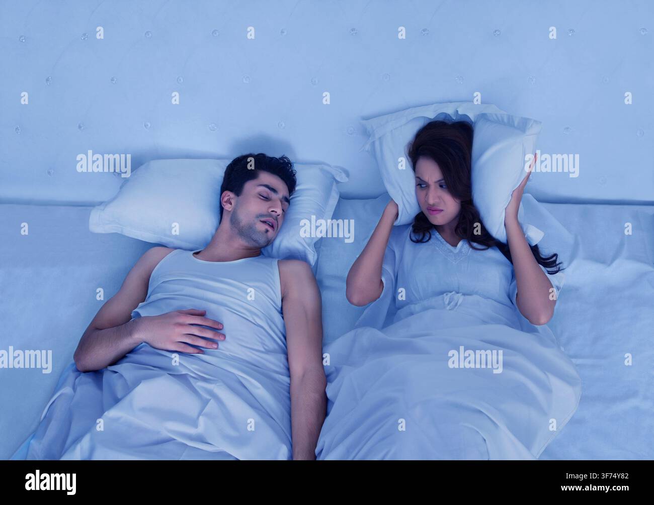 Angry woman looking at man snoring Stock Photo