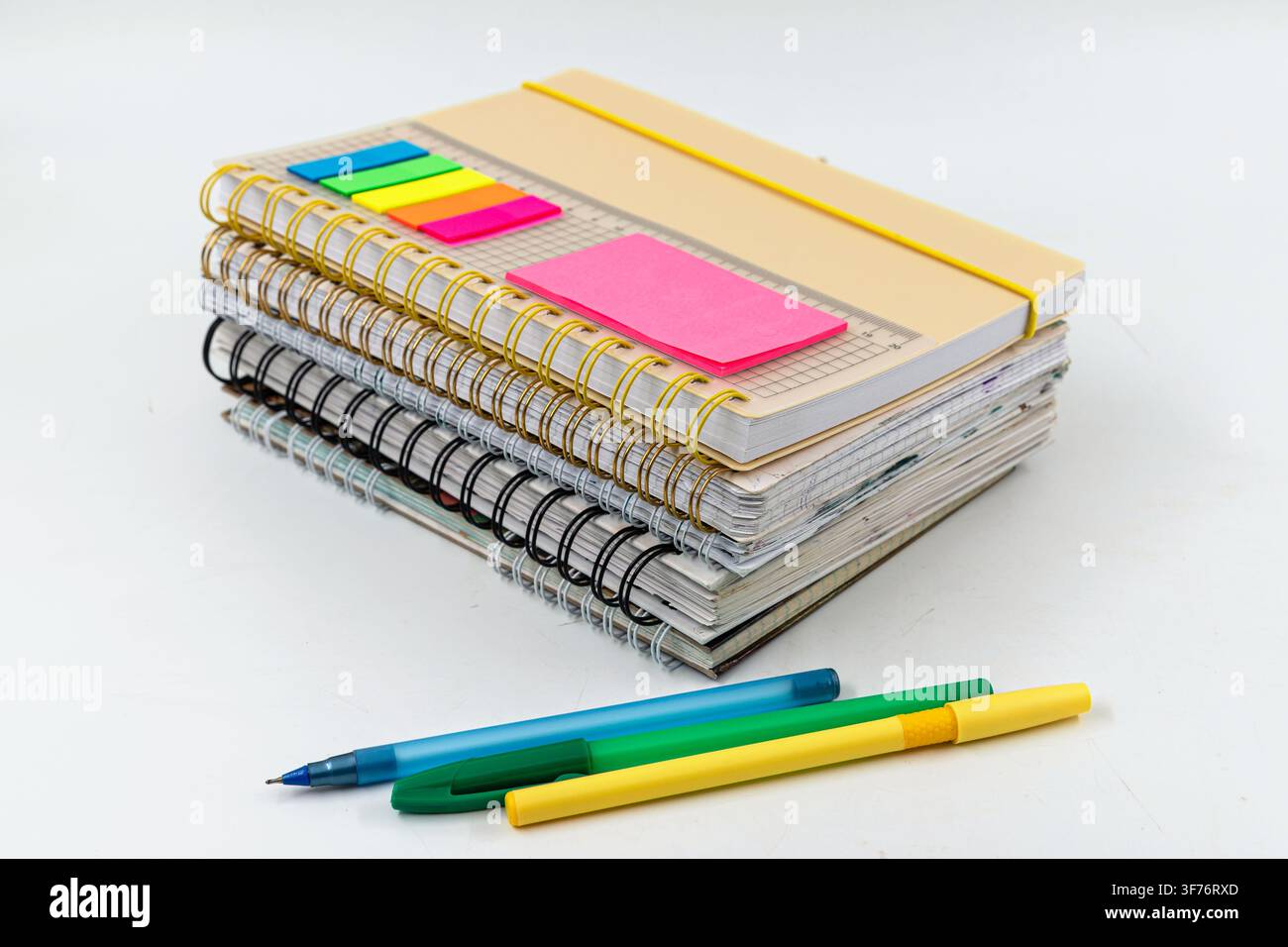 Stack of spiral notebooks with colorful pens and sticky page markers for studying Stock Photo