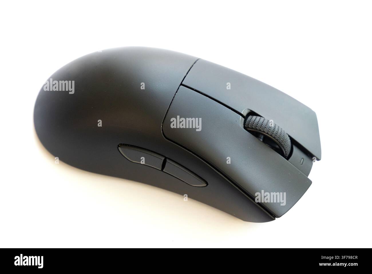 A modern black computer mouse sits on a white surface Stock Photo