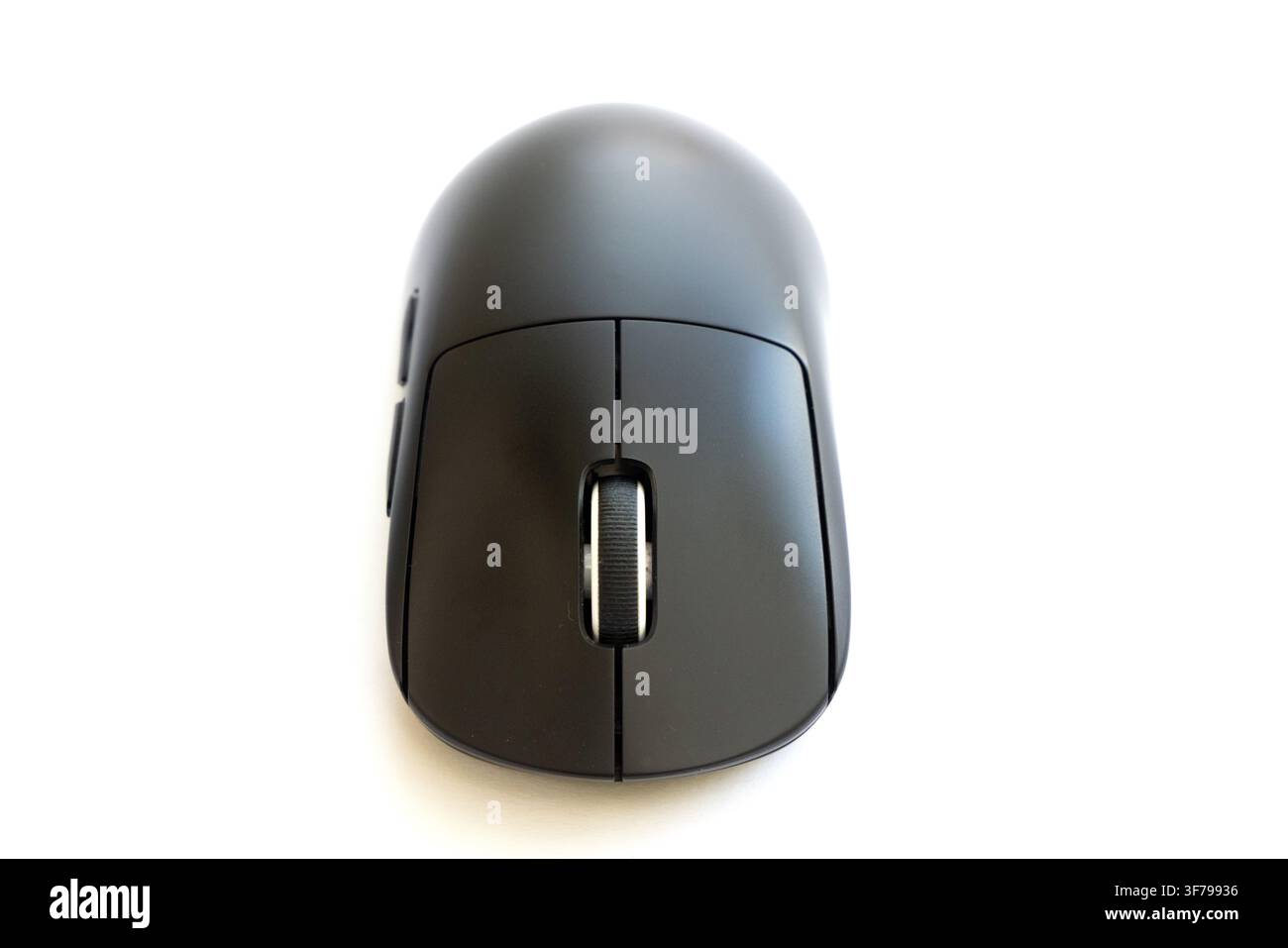 A modern black computer mouse sits on a white surface Stock Photo