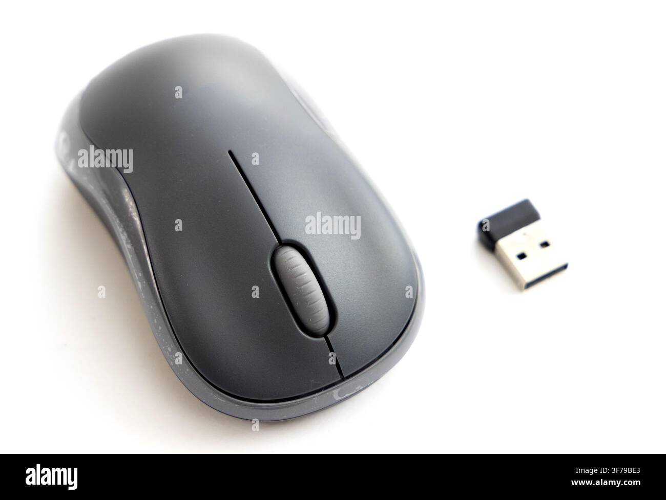A wireless computer mouse sits next to its USB receiver Stock Photo