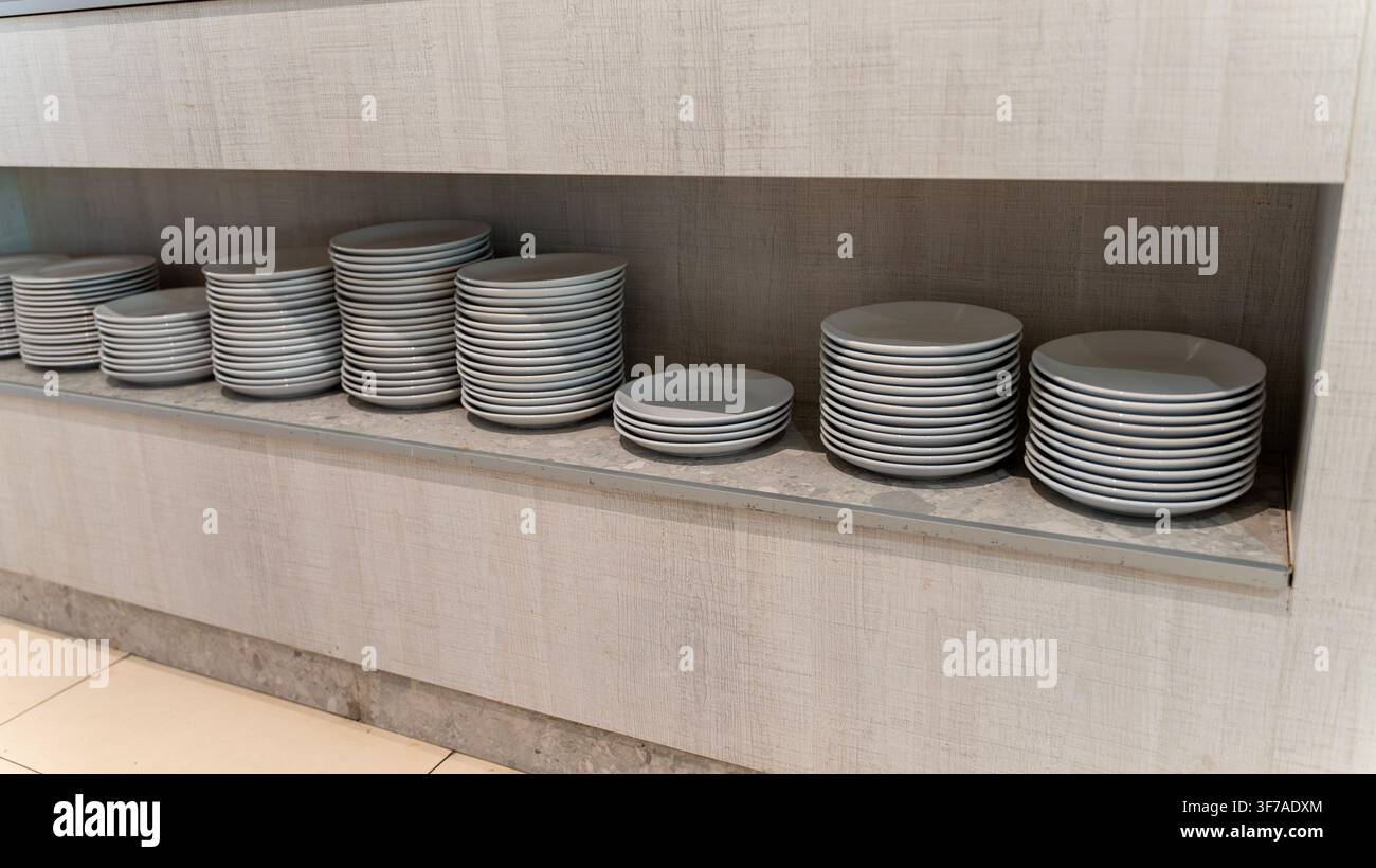 Stacks of White Ceramic Plates on Shelf in Restaurant Buffet Area Stock Photo