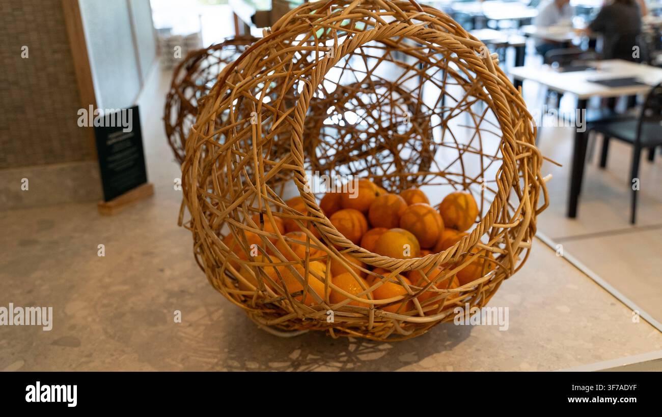 Wicker Basket with Fresh Oranges on Table in Restaurant Interior Stock Photo