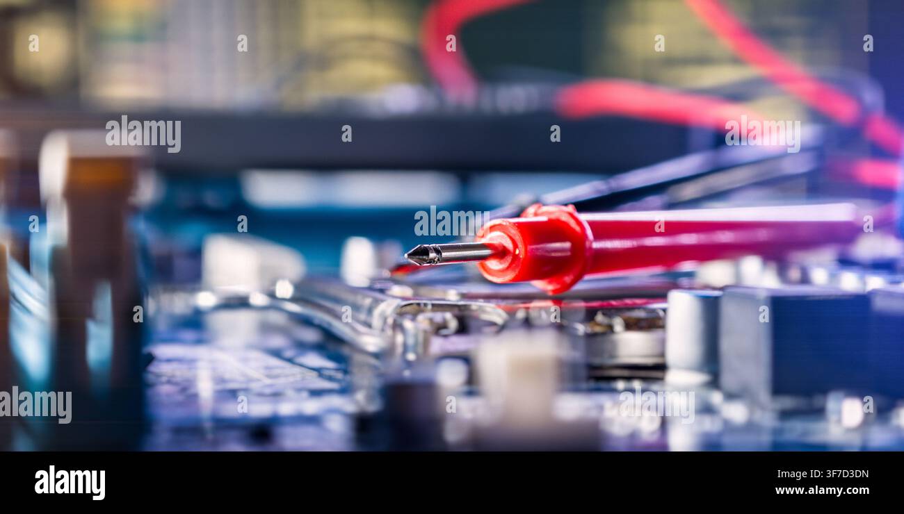 Macro view of a multimeter probe testing a printed circuit board. High-tech electronics maintenance. Stock Photo