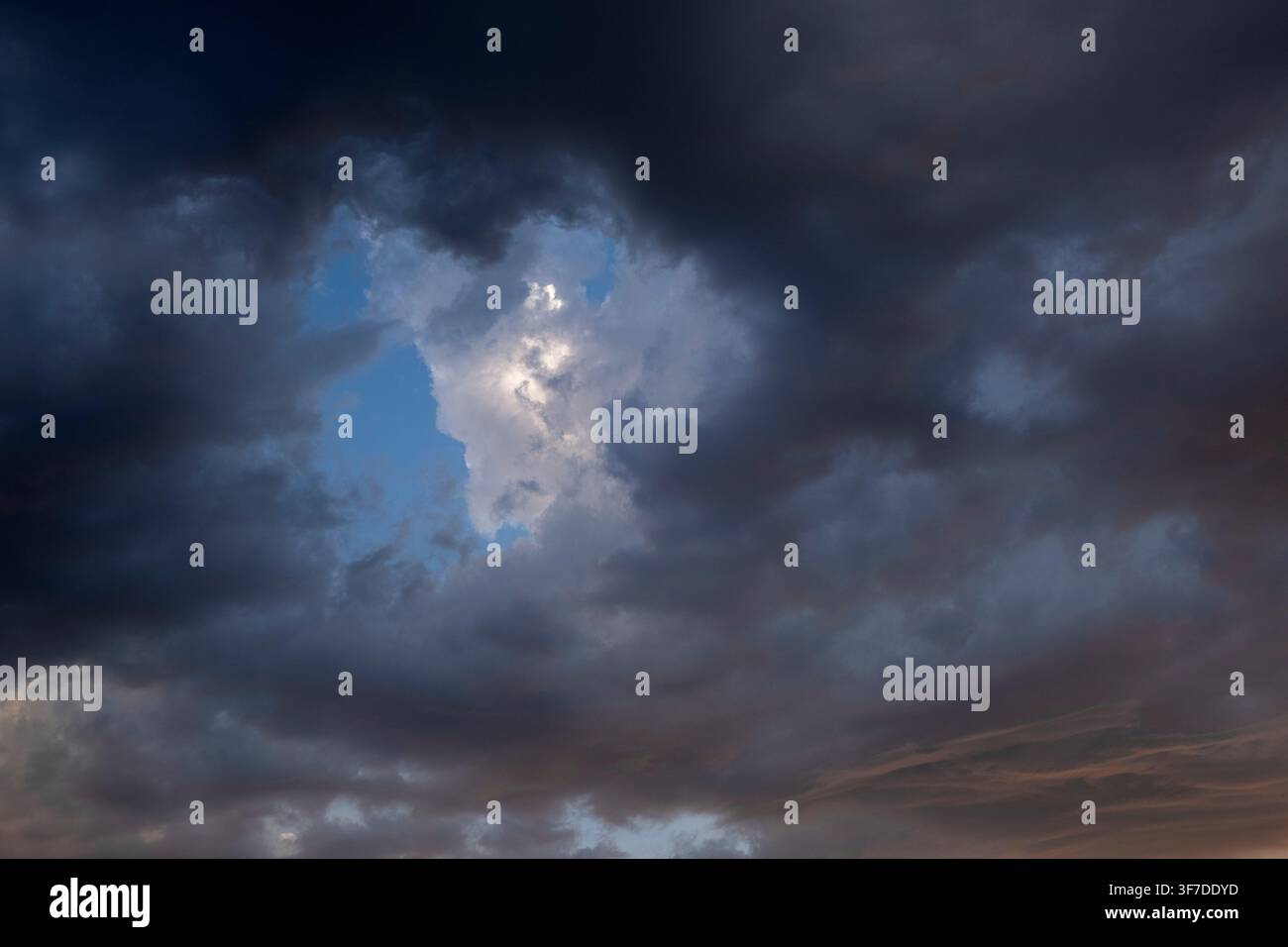 Dramatic storm clouds with blue sky and sunlight breaking through Stock Photo