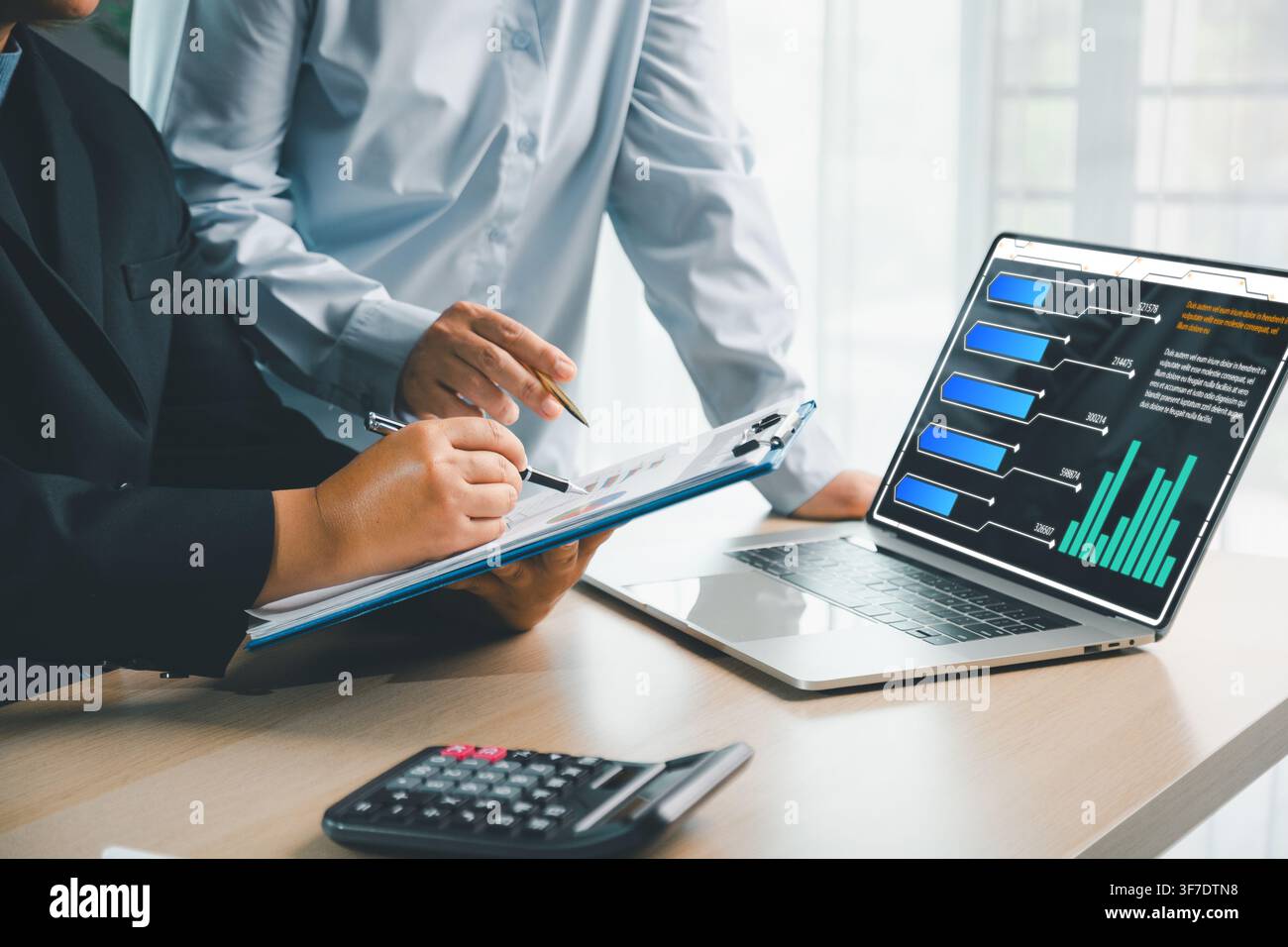 Business people reviewing financial documents with laptop dashboard, calculator and charts, showing digital finance analytics, accounting report and c Stock Photo