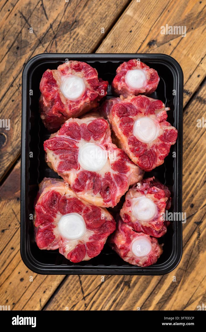 Fresh uncooked mutton lamb oxtail cuts with marrow bones packaged in tray, overhead composition on wooden background Stock Photo
