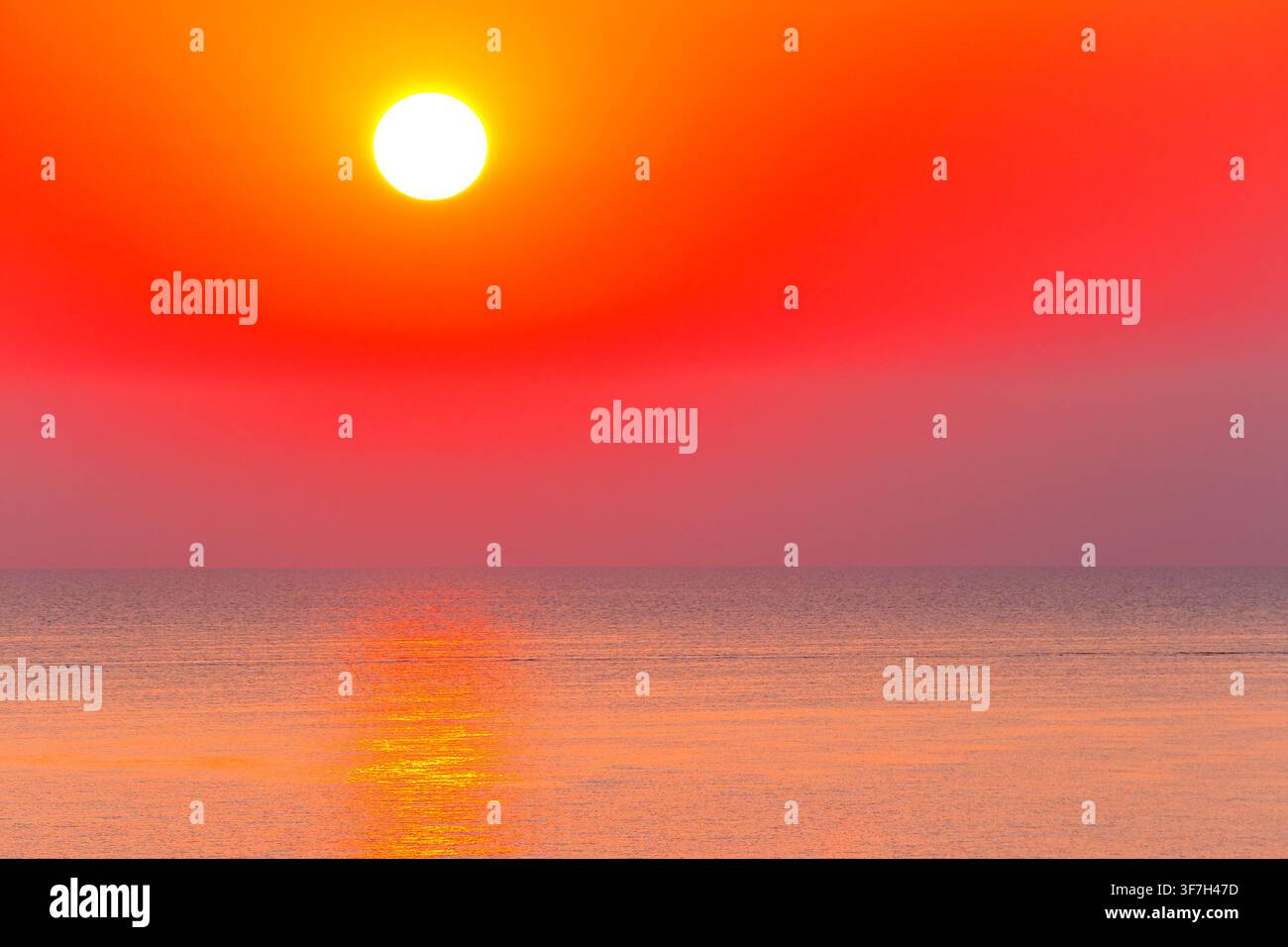 sunrise at the black sea. sun above horizon. reflection on the calm water. nature background in warm orange light Stock Photo
