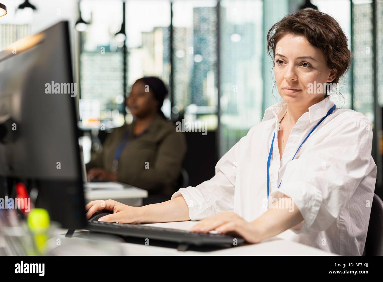 Smiling IT worker using PC at office desk, working with software development programming languages. Happy engineer using computer in startup company to do code testing and quality assurance Stock Photo
