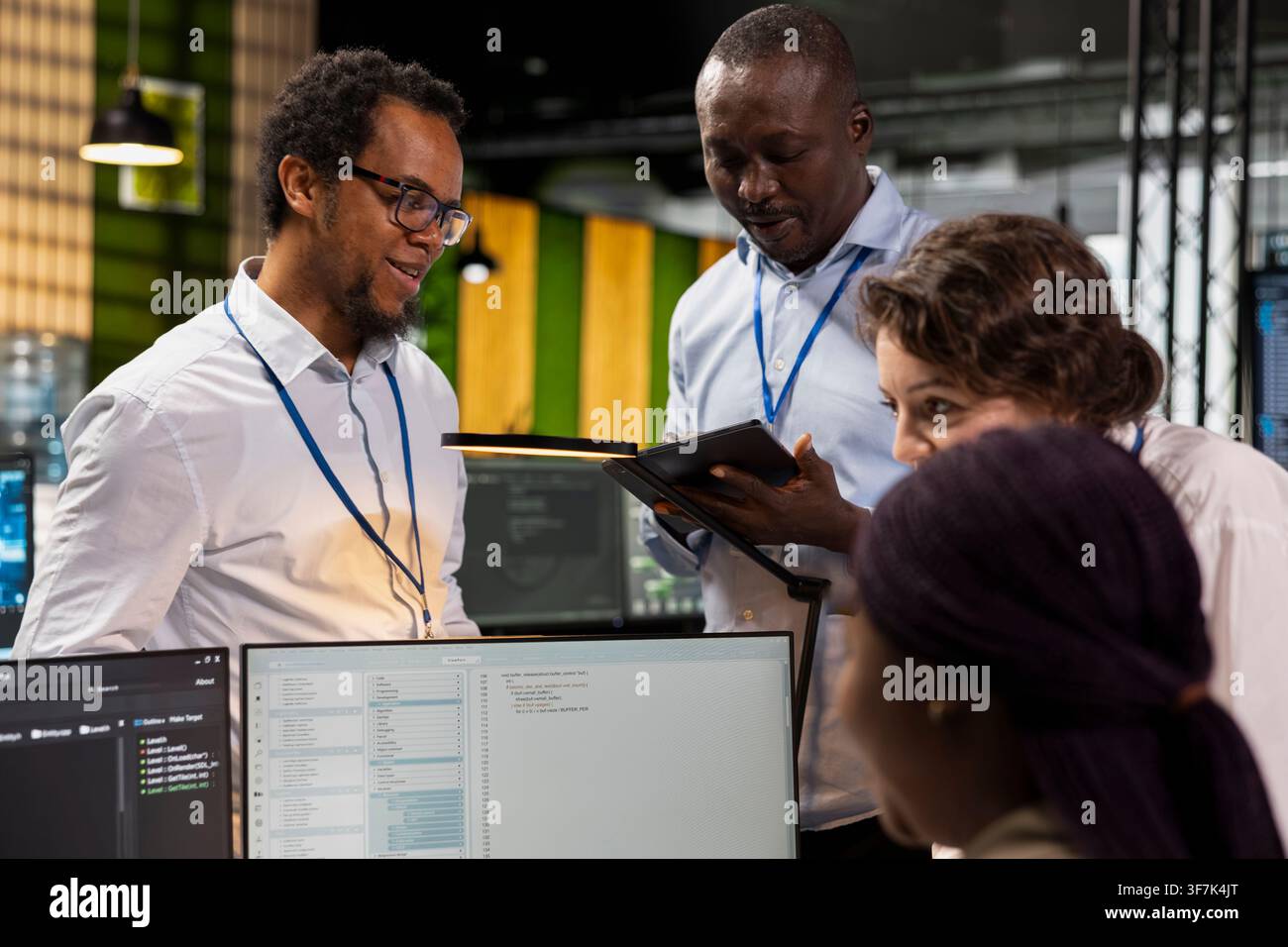 Engineering team doing brainstorming, using computer in workplace to do maintenance on neural networks. Tech startup office teamworking colleagues using AI machine learning systems on PC Stock Photo