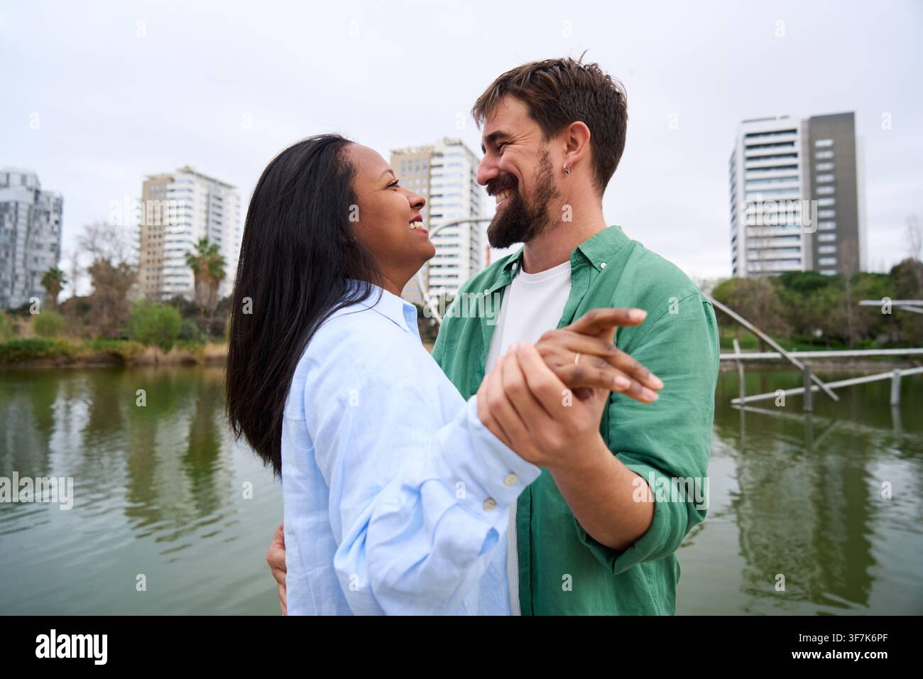 Happy multiracial couple dancing by lake in city park. Stock Photo
