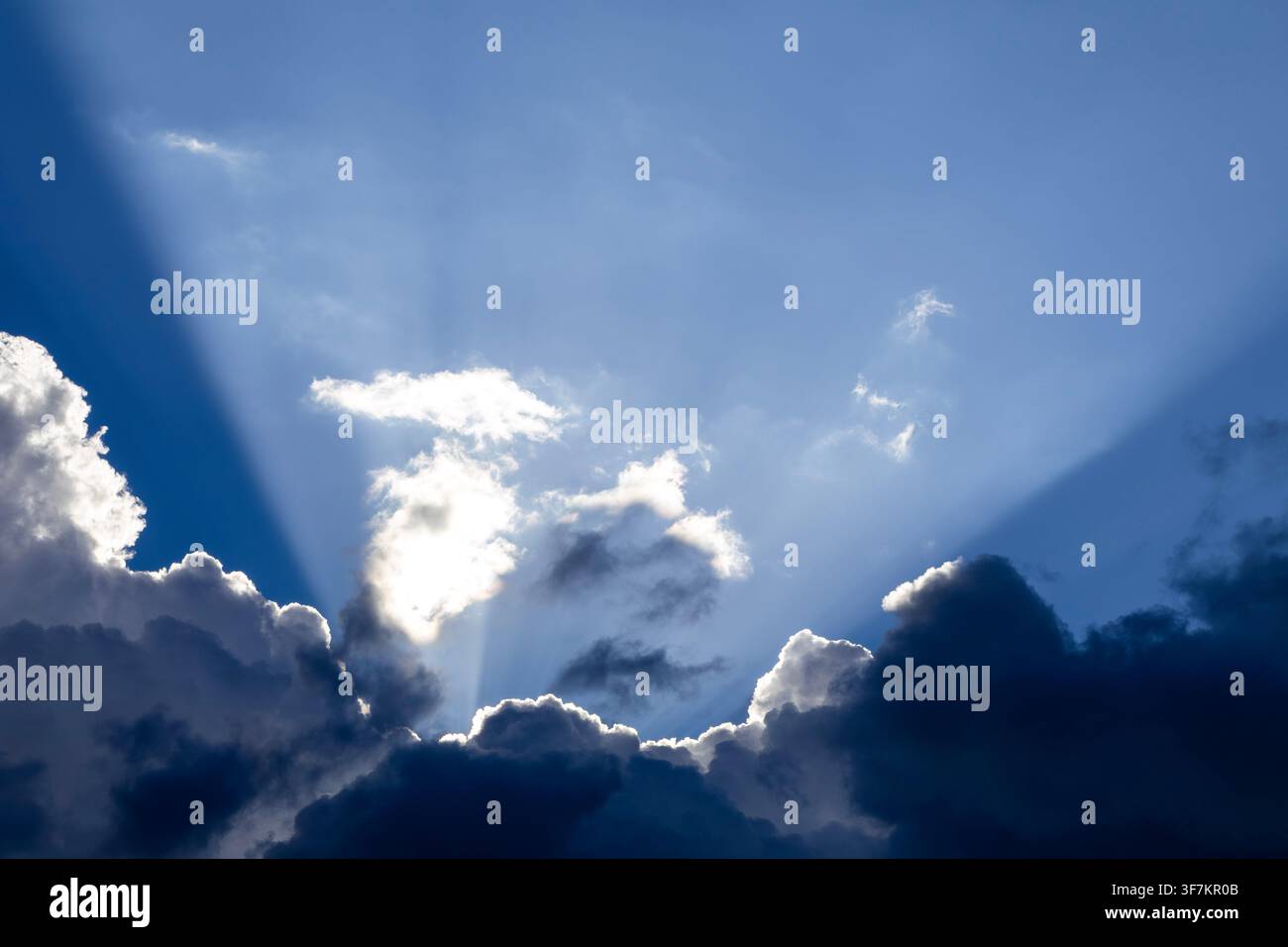 Dramatic God crepuscular rays streaming through dense dark storm clouds Stock Photo