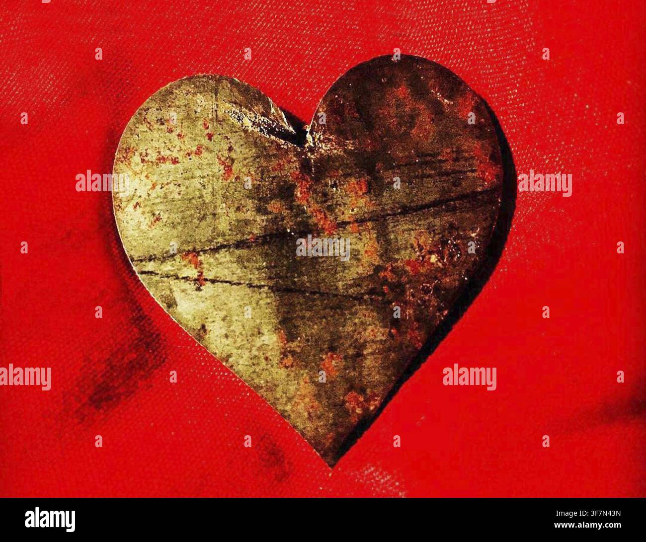 Rustic metal heart on a vibrant red background Stock Photo