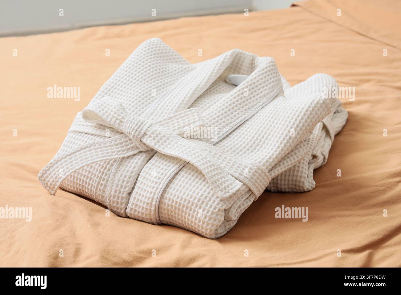 Folded waffle bathrobes on bed in room Stock Photo