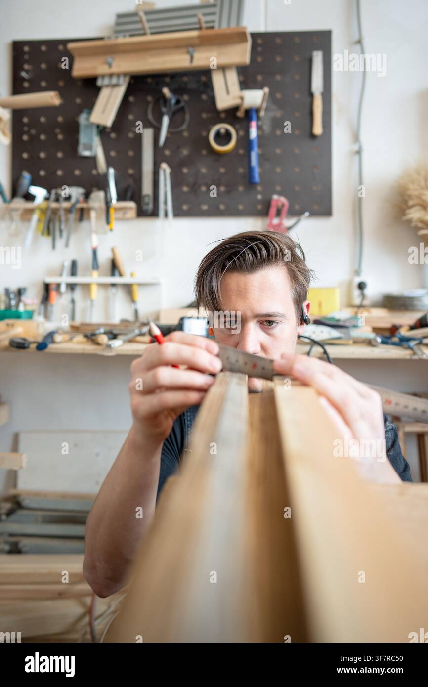 Man woodworker precisely measuring wooden board patch replacement for antique window frame. Stock Photo