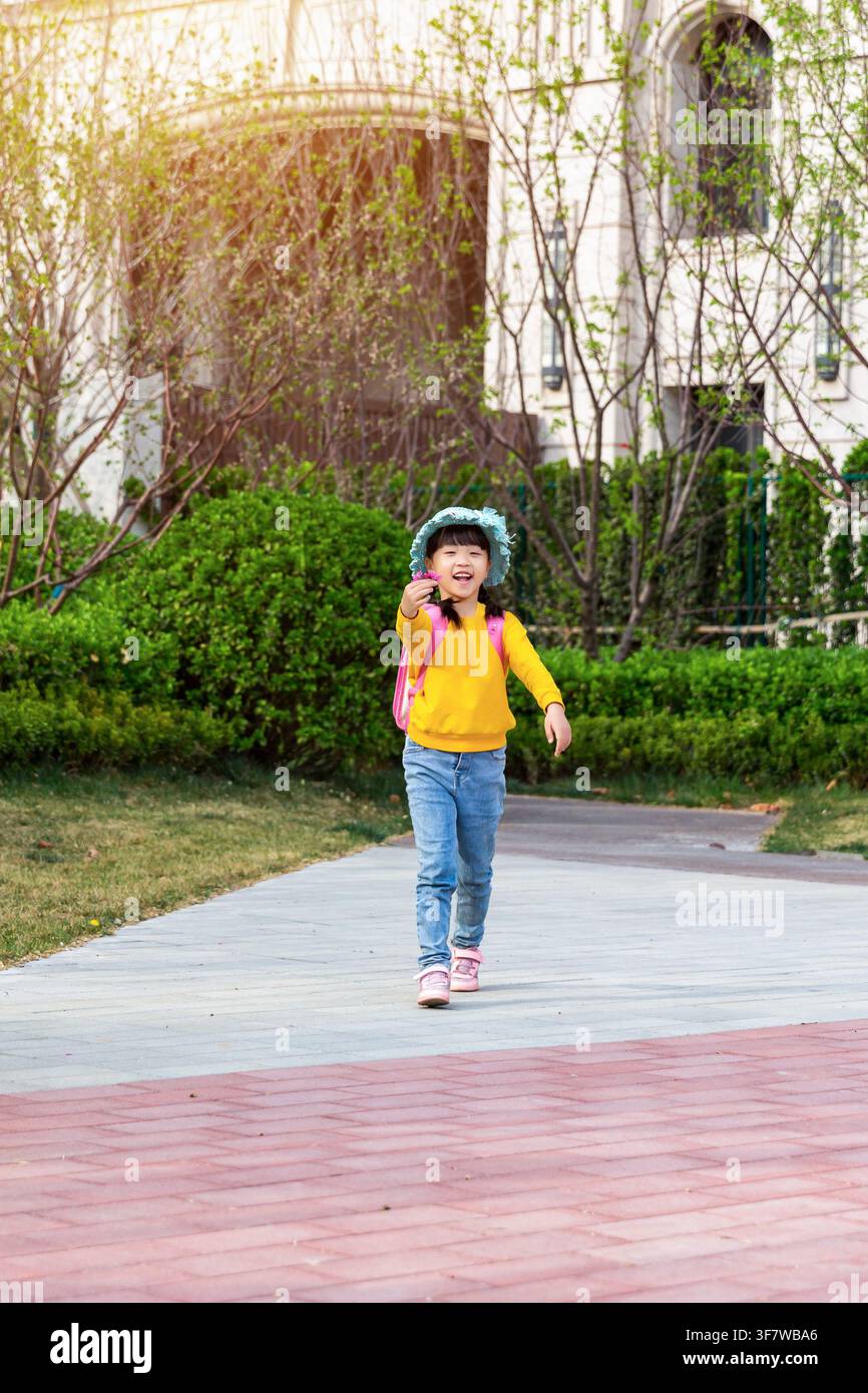 Joyful Young East Asian Girl in Yellow Sweater Walking Towards Camera ...