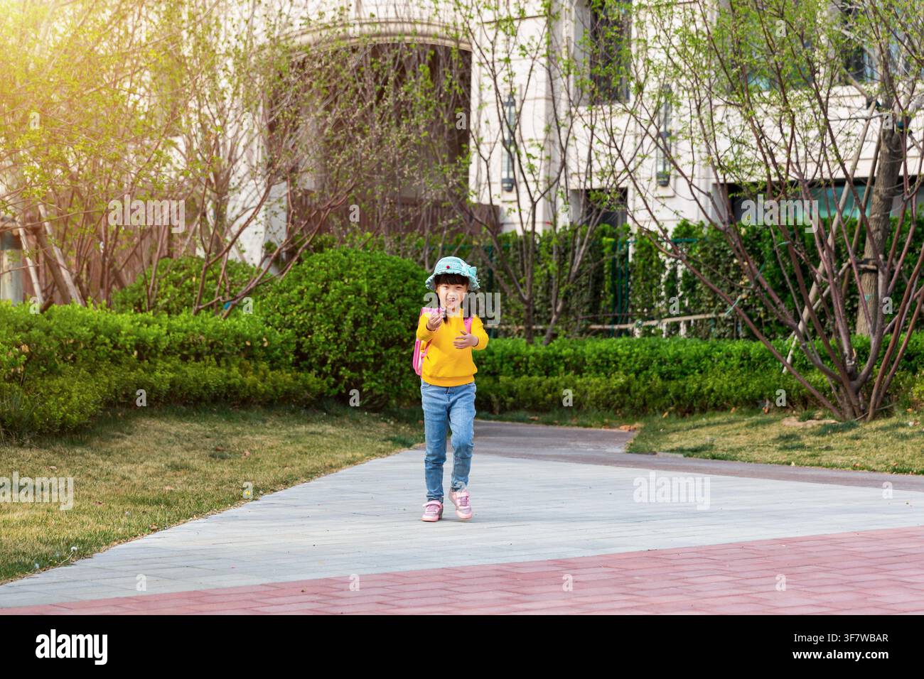 Joyful Young East Asian Girl in Yellow Sweater Walking Towards Camera ...