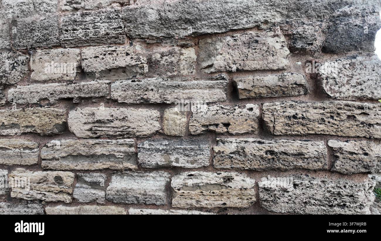 Ancient stone wall with rough texture and weathered bricks Stock Photo