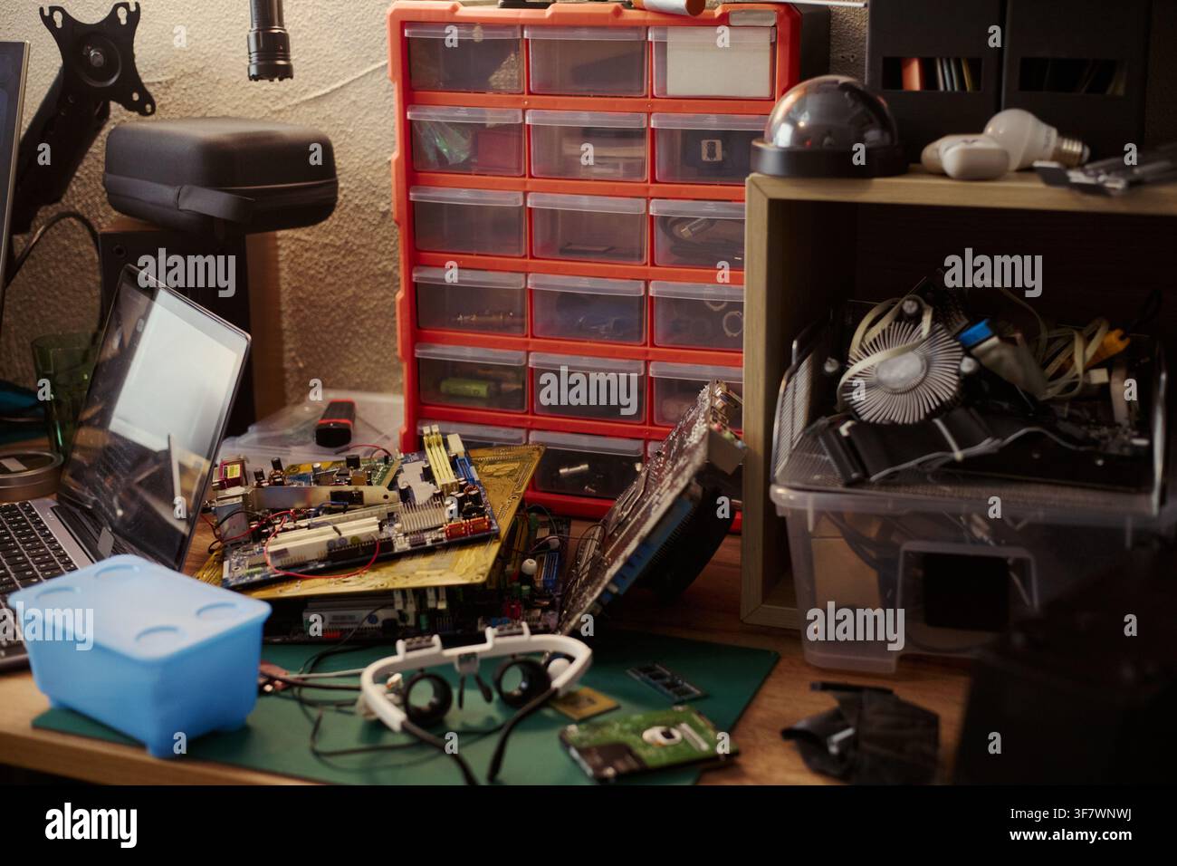 Computer hardware components lying on messy workshop desk with laptop and tools, representing electronics repair. Image suitable for IT support and hardware engineering services Stock Photo