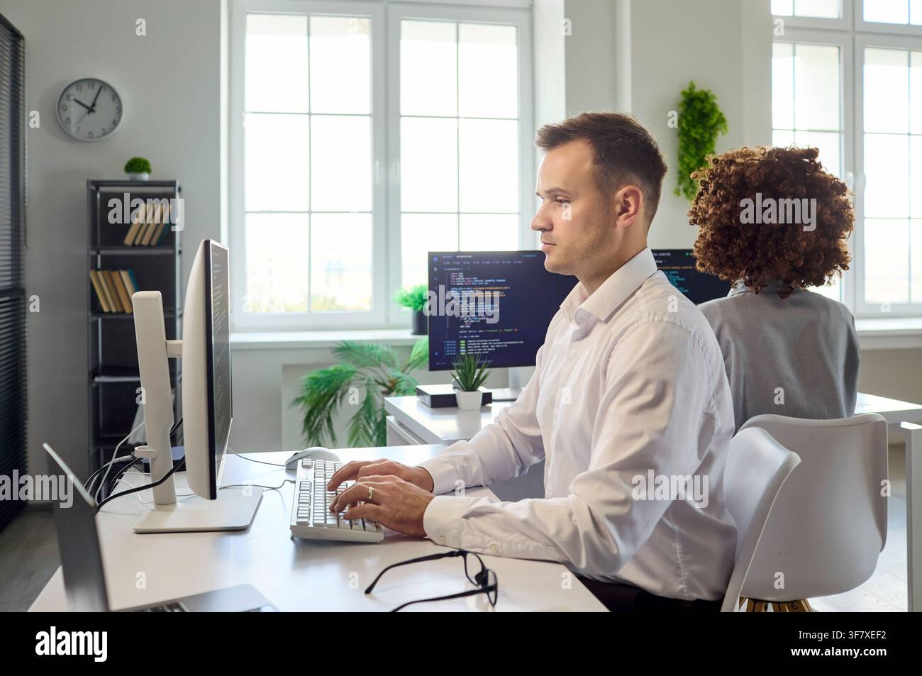 Software developers coding at computers in modern office, teamwork focus today Stock Photo