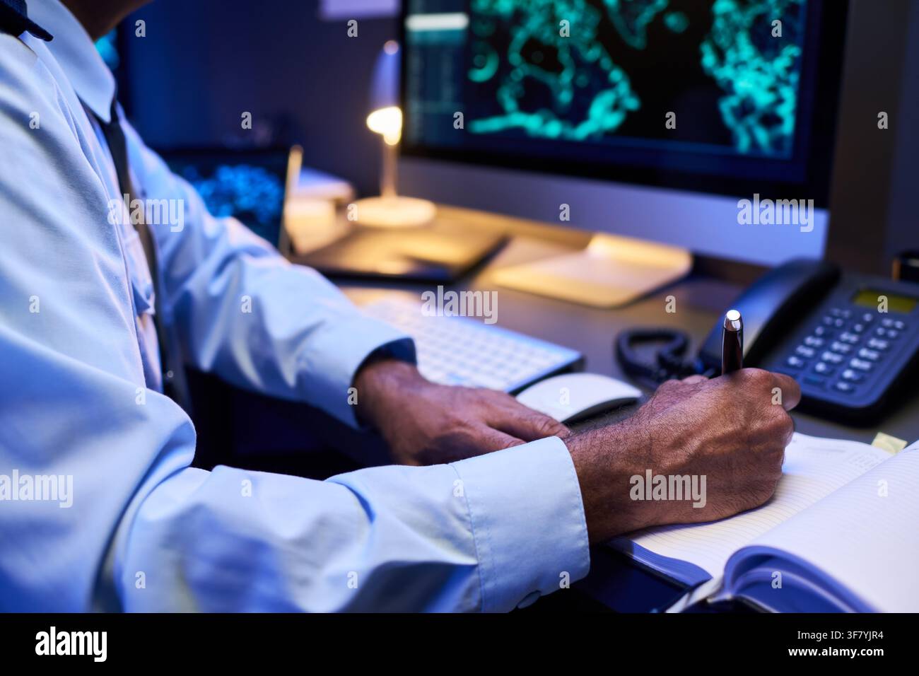 Security Guard Writing in Logbook in Control Room Stock Photo