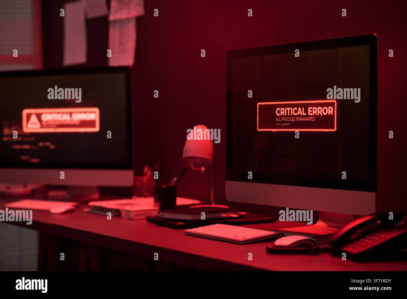 Computer Screens Showing Critical Error Message in Dark Office Stock Photo