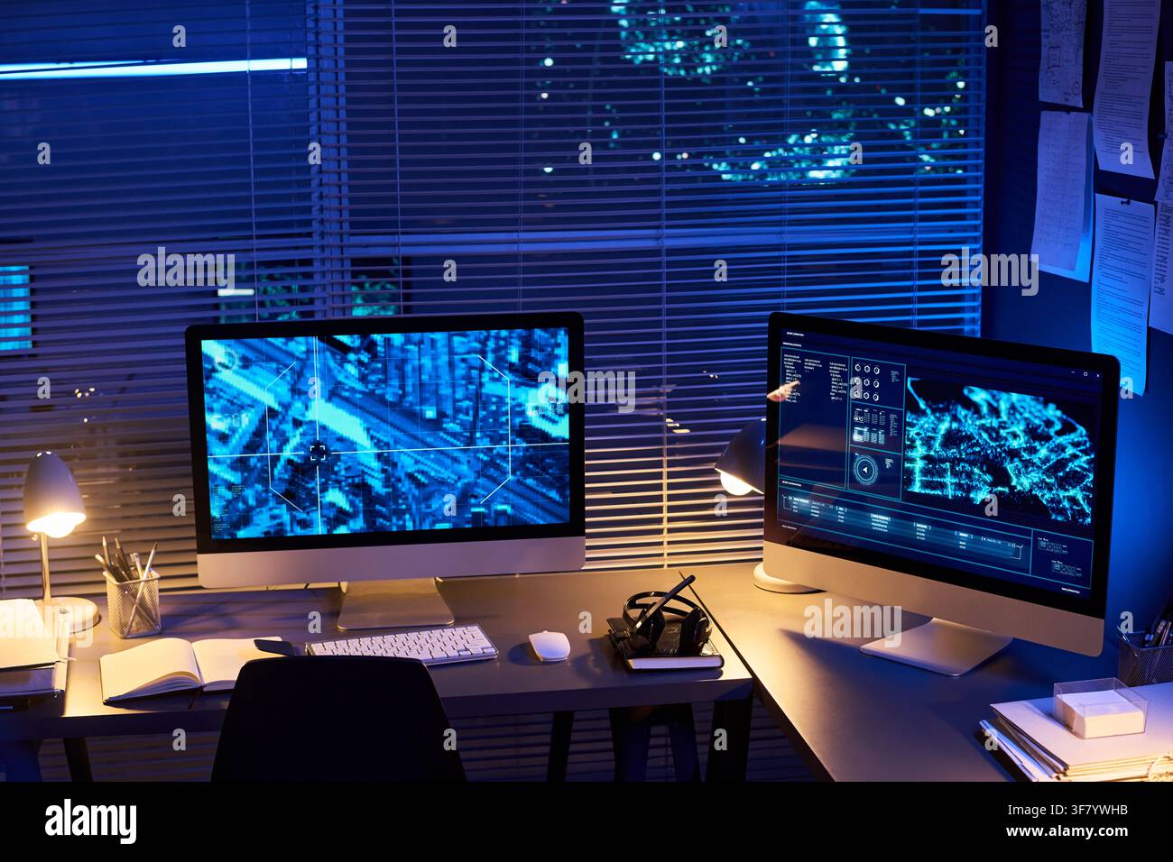 Computer Monitors Displaying Digital Maps in Dark Security Control Room Stock Photo