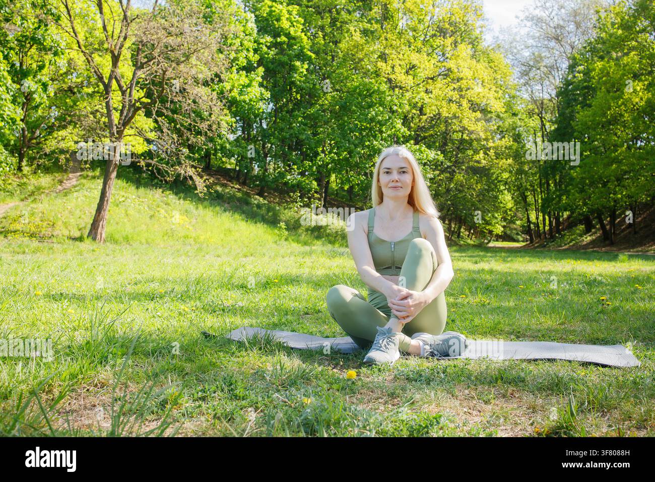 Beautiful middleaged blonde sporty woman on outdoor training in green Stock Photo