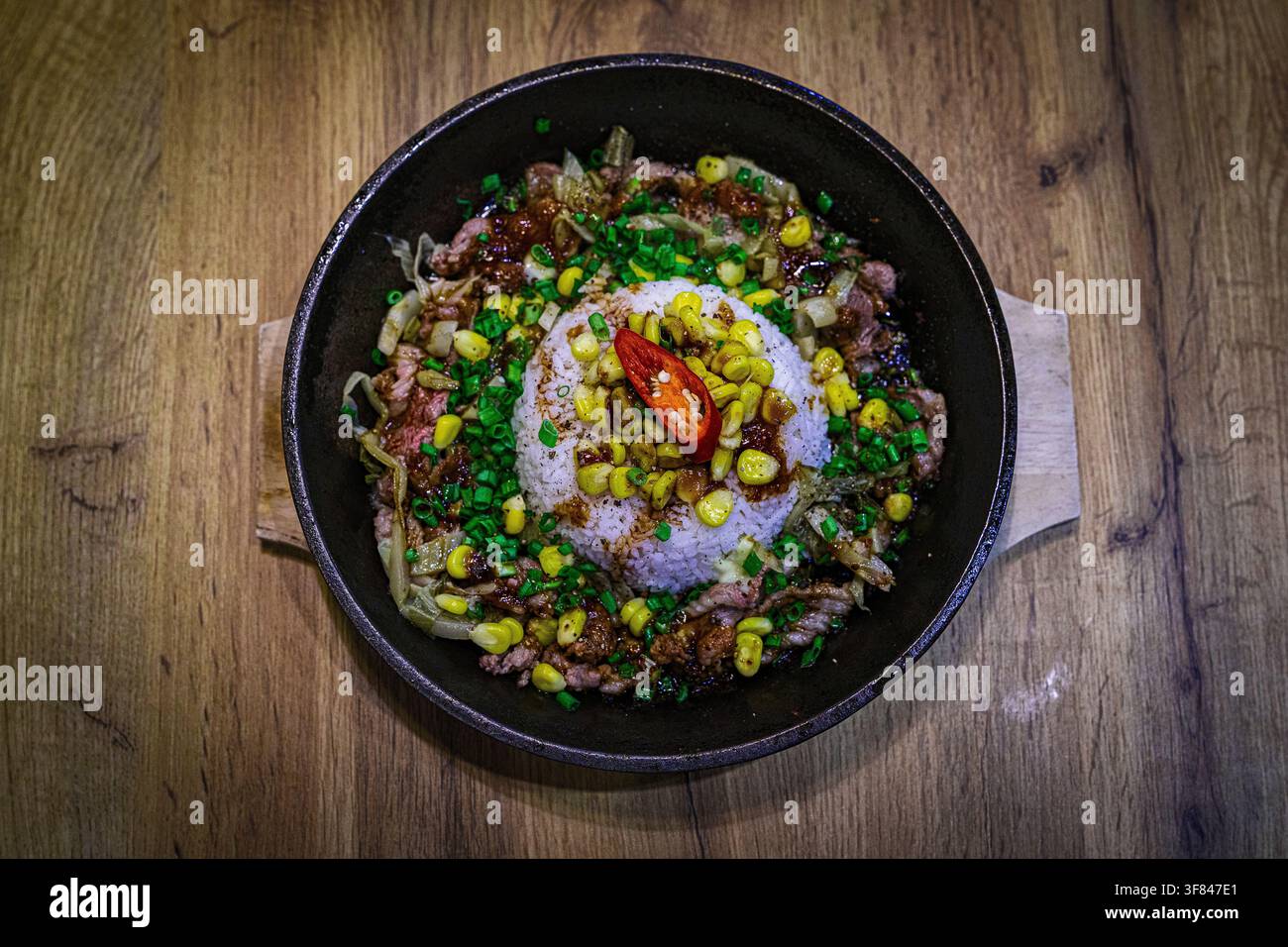 Delicious Vietnamese fried rice served with beef and vegetables on a wooden table in Vietnam Stock Photo
