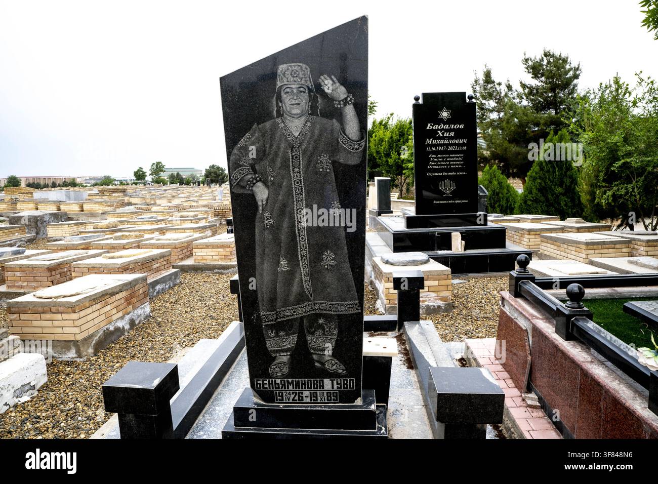 Grave marker in Bukhara Jewish cemetery with detailed engraving and surrounding tombstones Stock Photo