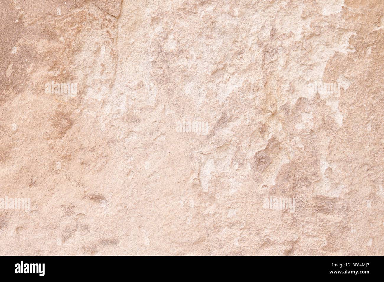 Abstract texture of an ancient weathered stone wall with beige plaster cracks Stock Photo