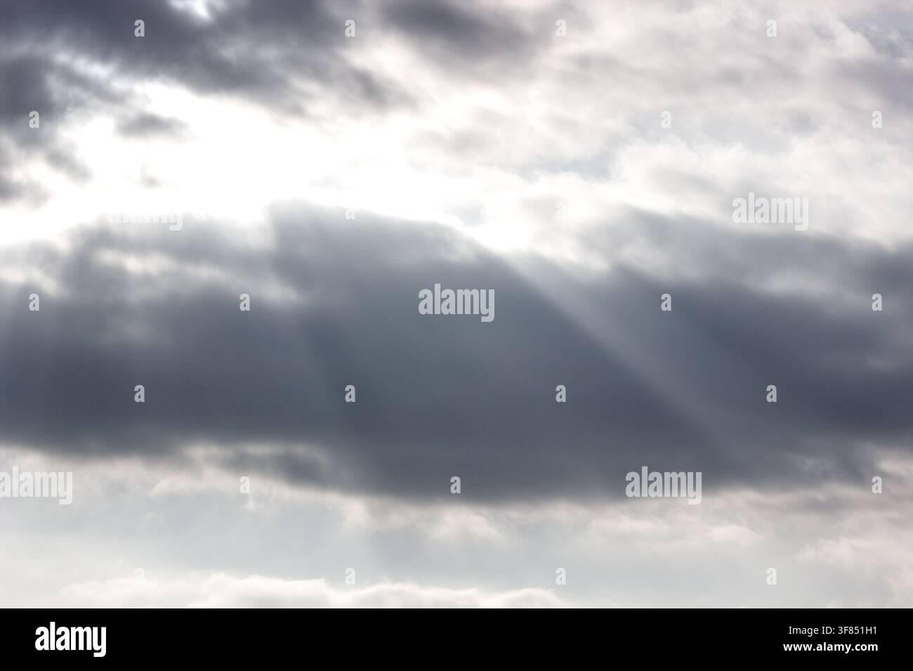 Sunbeams breaking through dramatic clouds in the sky. Stock Photo