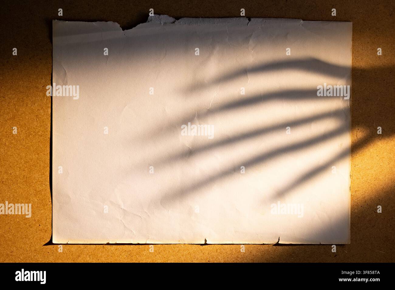 Vintage torn paper with eerie hand shadow on warm background for Halloween poster or horror flyer Stock Photo