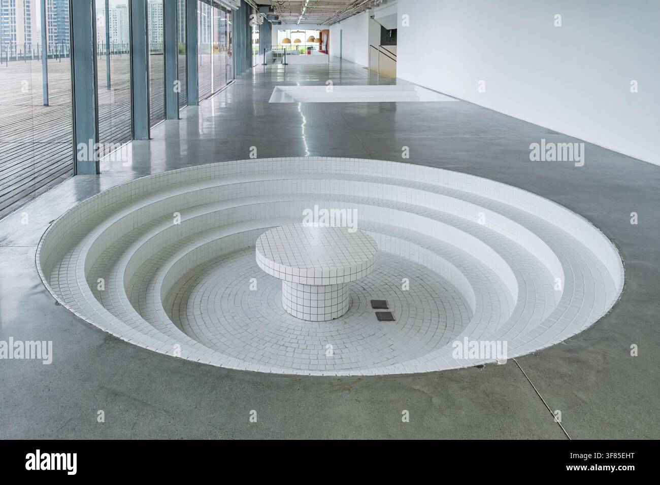 Minimalist modern interior with circular sunken seating, white tiled surfaces and polished concrete floor. Contemporary architecture, geometric design Stock Photo