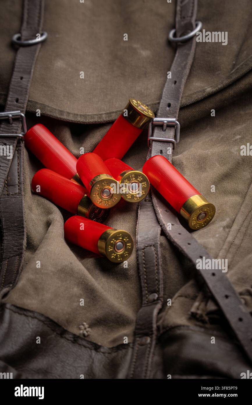 Red 12 gauge shotgun shells lying on a vintage canvas hunting backpack. Stock Photo