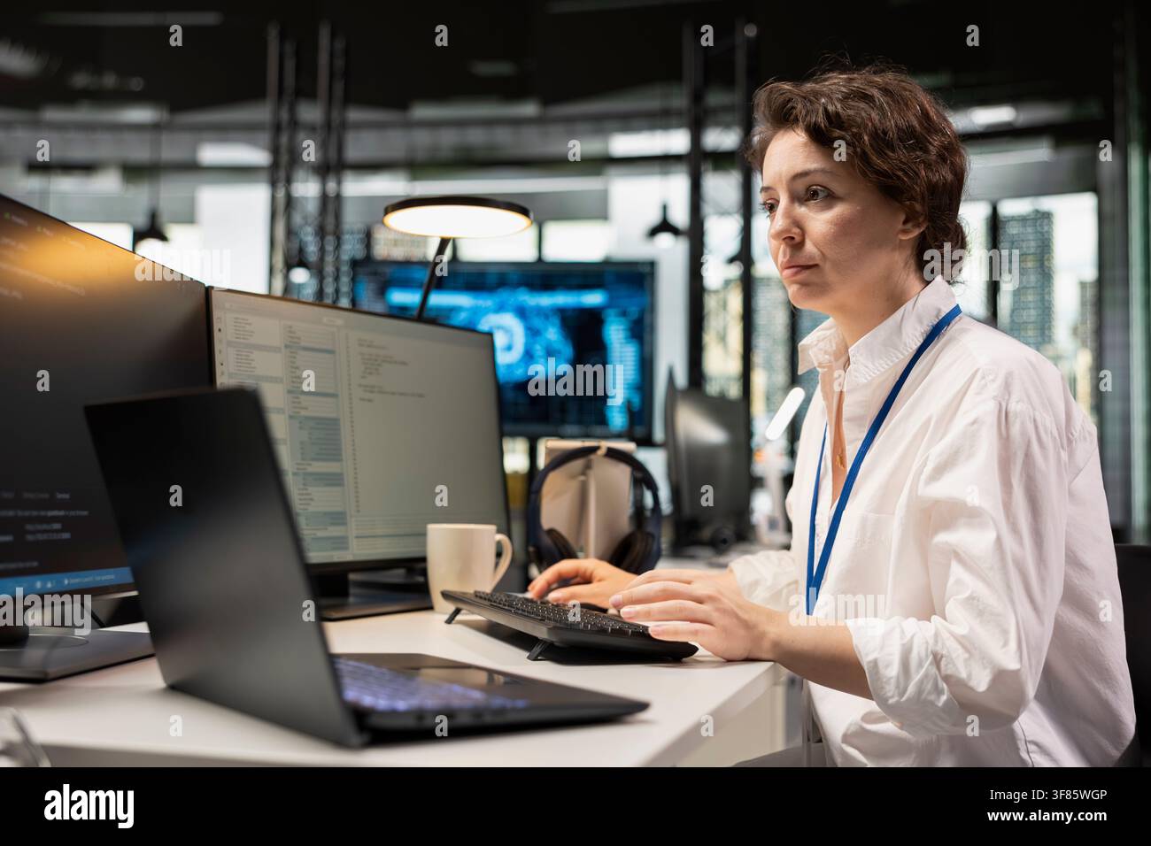 Programmer at office desk using machine learning programming languages displayed on PC screen. Worker using computer in AI company workspace to run deep learning algorithms simulations Stock Photo