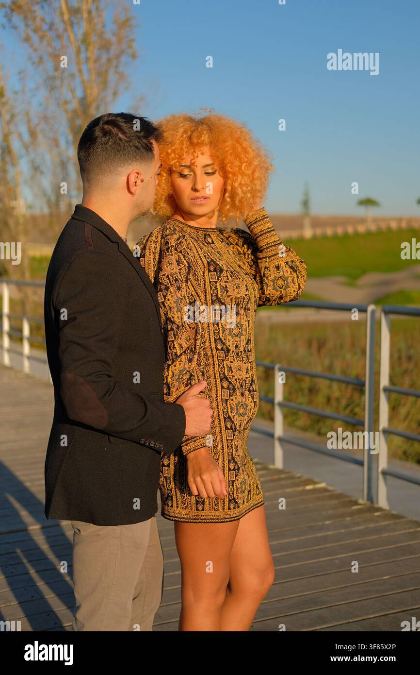 Couple embracing on a boardwalk, enjoying a warm golden hour outdoors Stock Photo