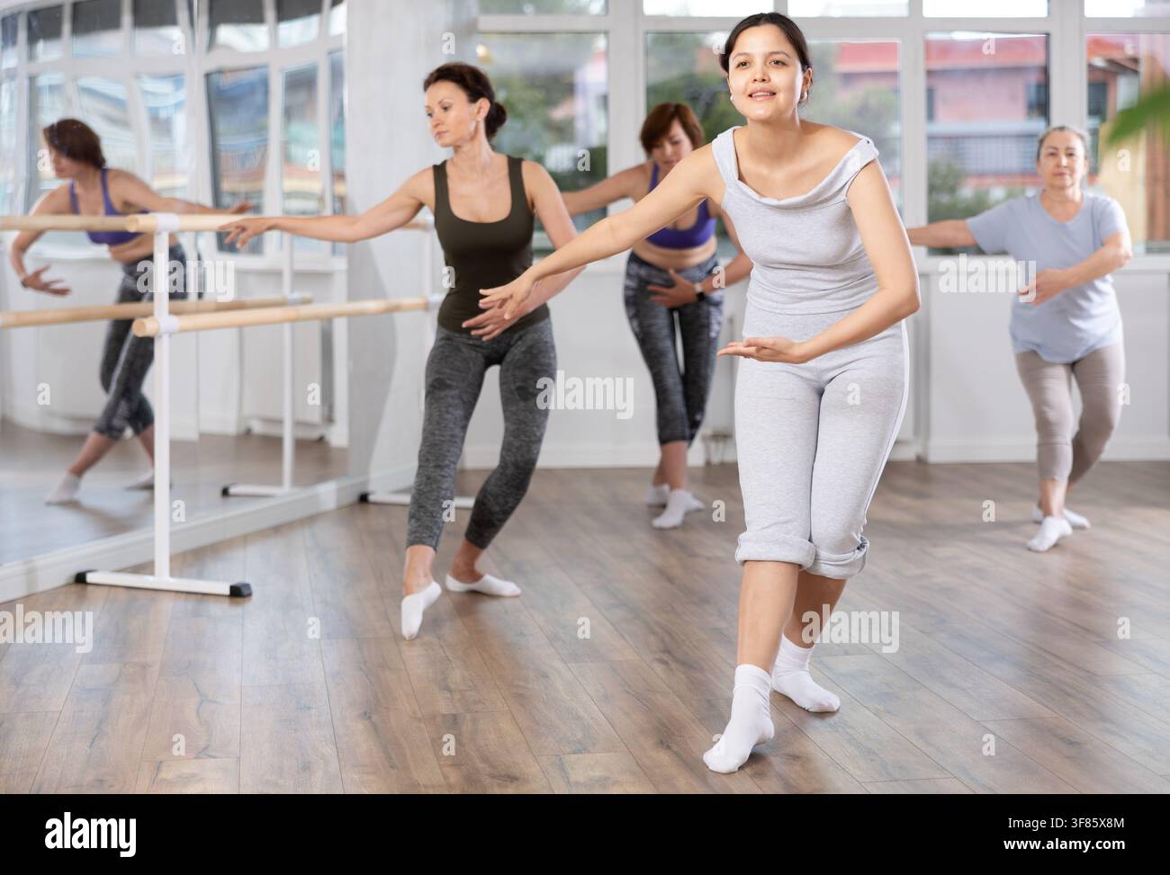 Young female amateur ballet dancer practicing moves at group session Stock Photo
