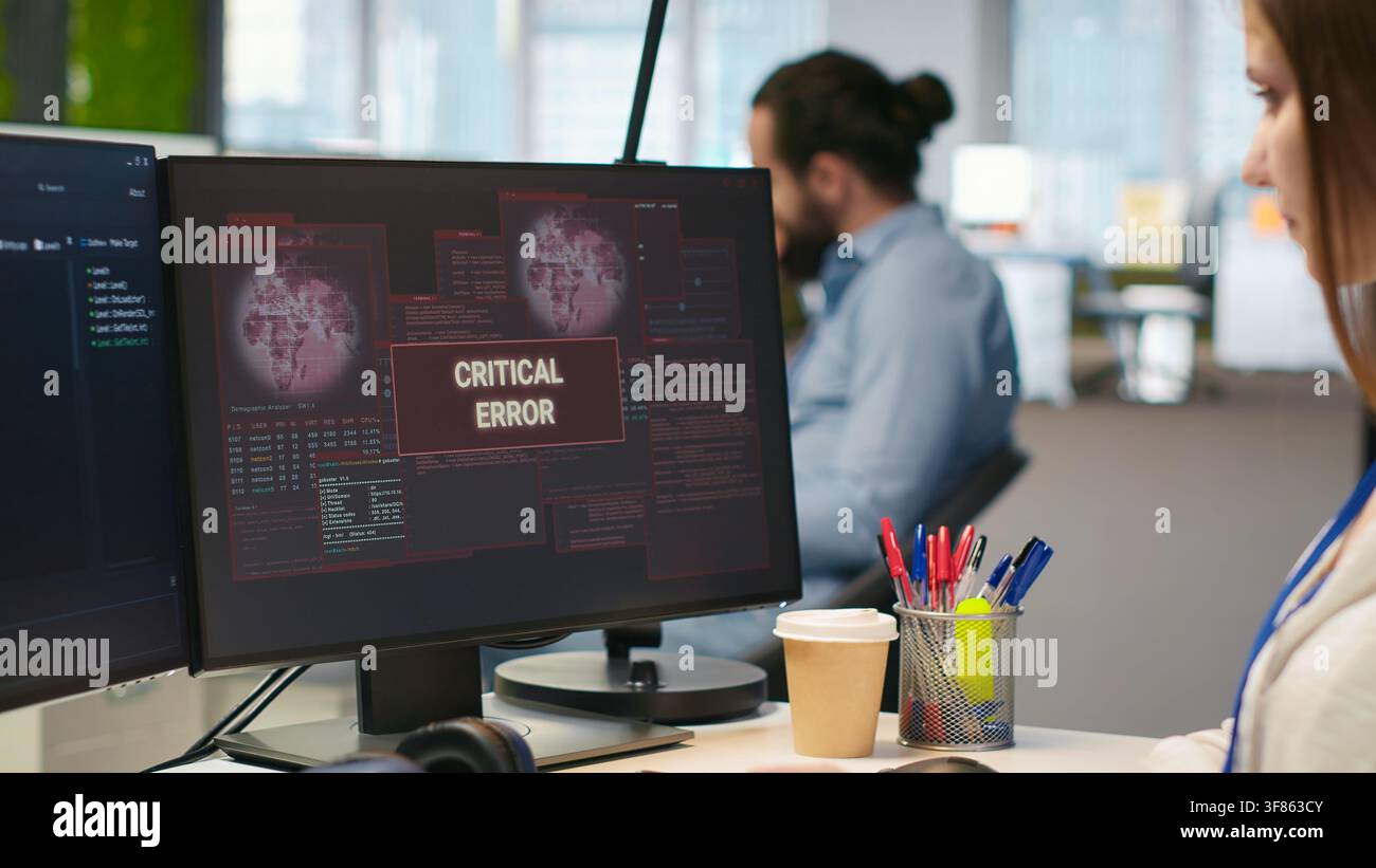 Female engineer in startup office struggling to fix critical error warning popup. Intern doing maintenance on computer glitches while coding in software development agency, camera A Stock Photo