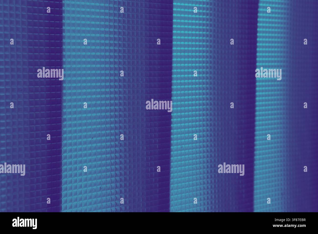 Close-up of blue and purple vertical blinds featuring a grid texture and striped lighting. Modern abstract background suitable for technology or inter Stock Photo